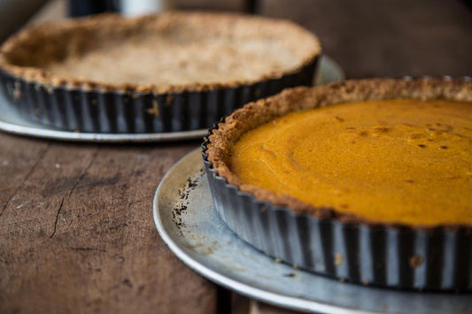 Slice of pumpkin custard tart with toasted pecans on a coconut-and-date base.