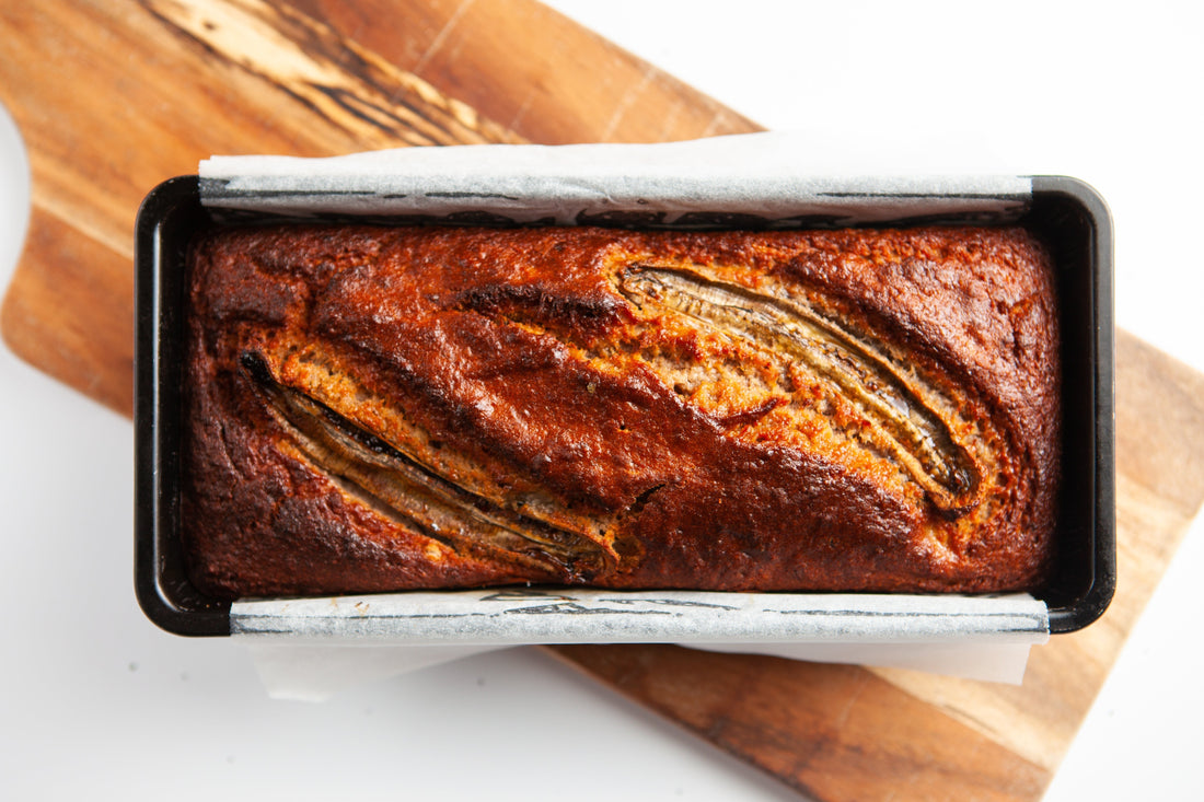 Sliced banana bread topped with caramelised banana slices and walnuts.