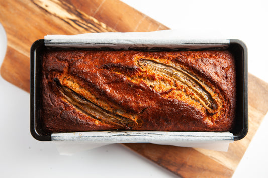 Sliced banana bread topped with caramelised banana slices and walnuts.