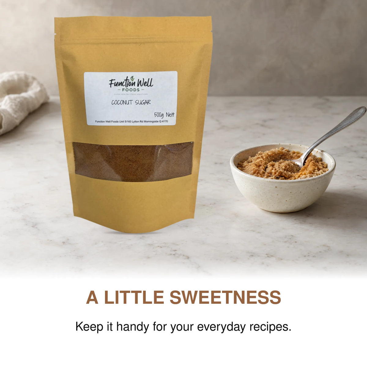 Function Well Foods Organic Coconut Sugar 500g packaging on a kitchen bench beside a small dish of organic coconut sugar.