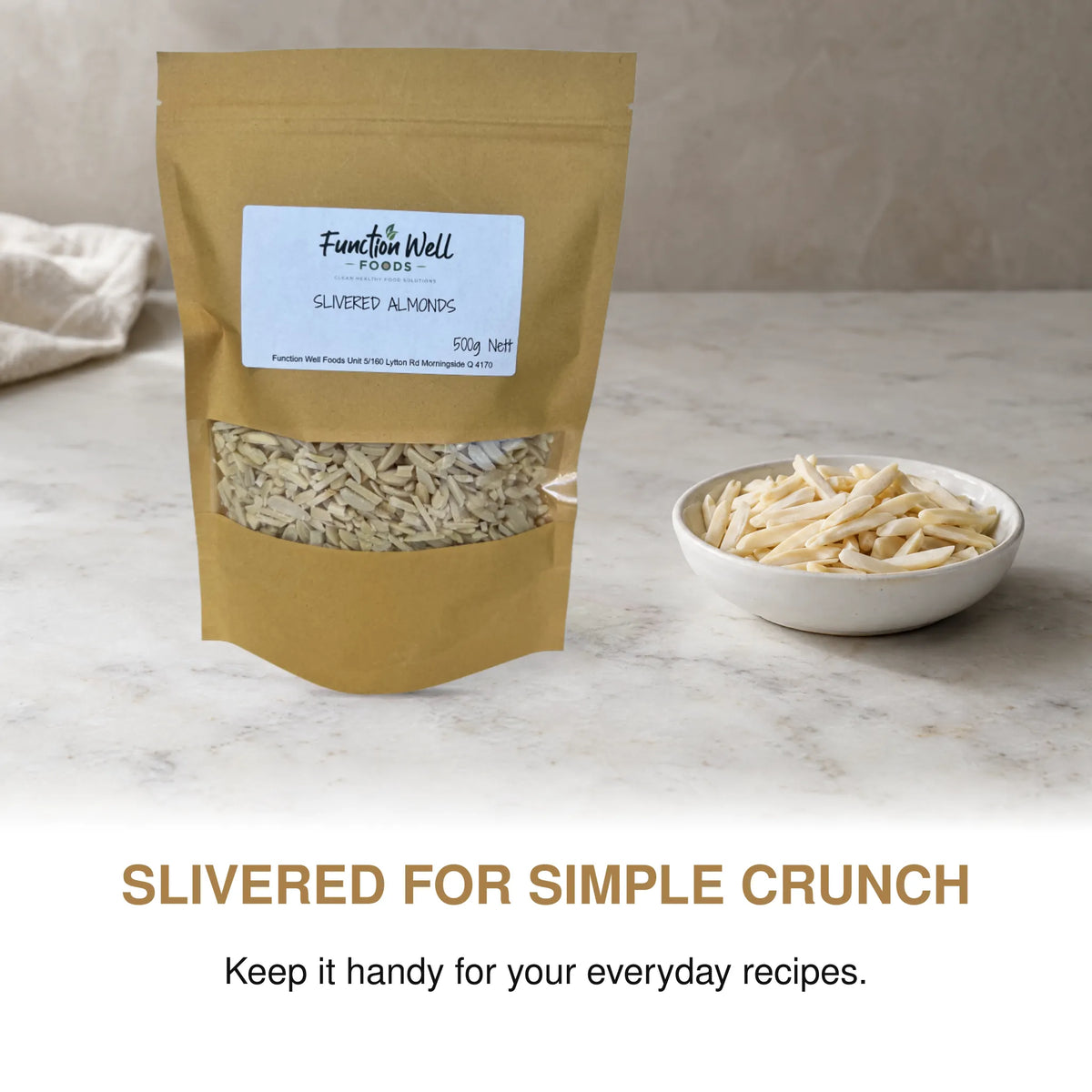 Function Well Foods Slivered Almonds 500g packaging on a kitchen bench beside a small dish of blanched slivered almonds.